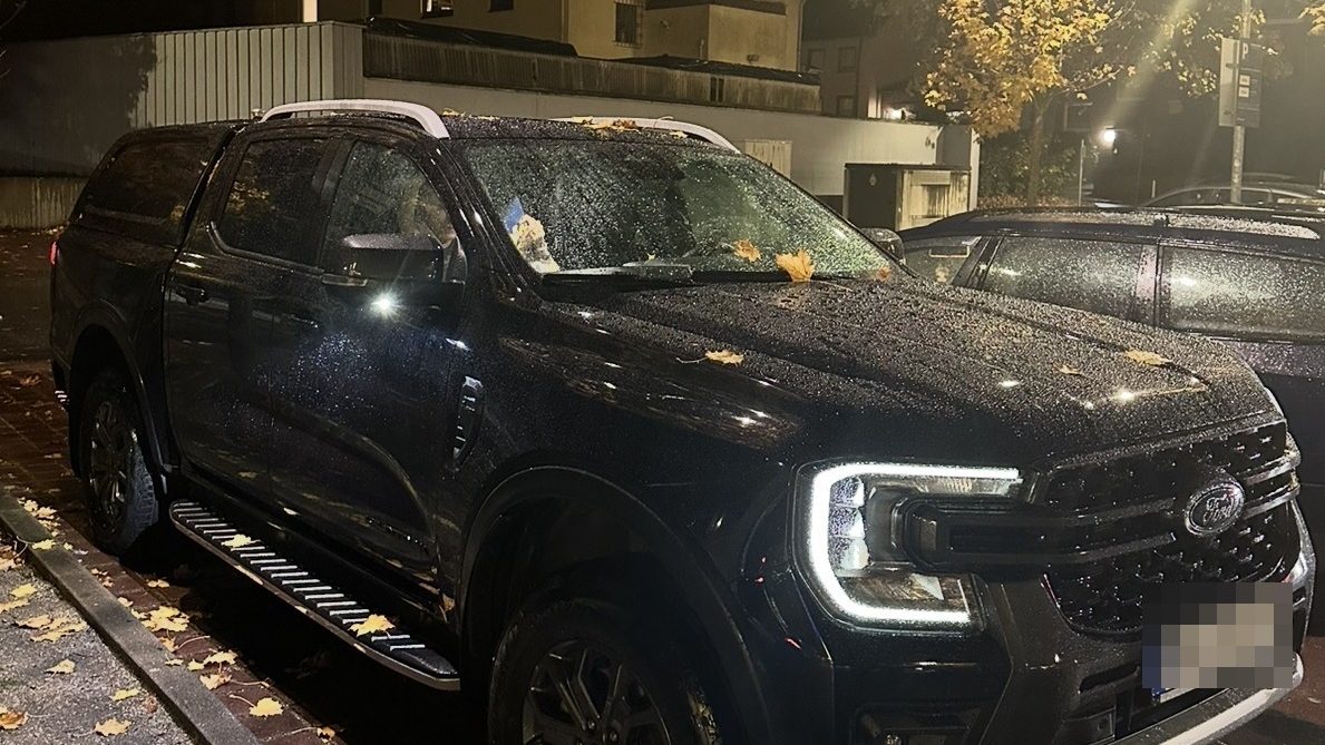 Unser Einsatzfahrzeug bei Nacht am Straßenrand, Laternenlicht auf nassem Lack